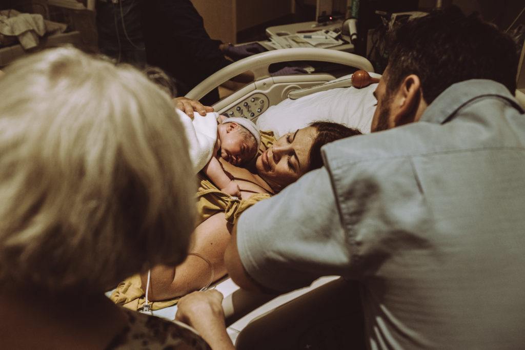 Grandmother and husband gazing at mother and newborn baby 
