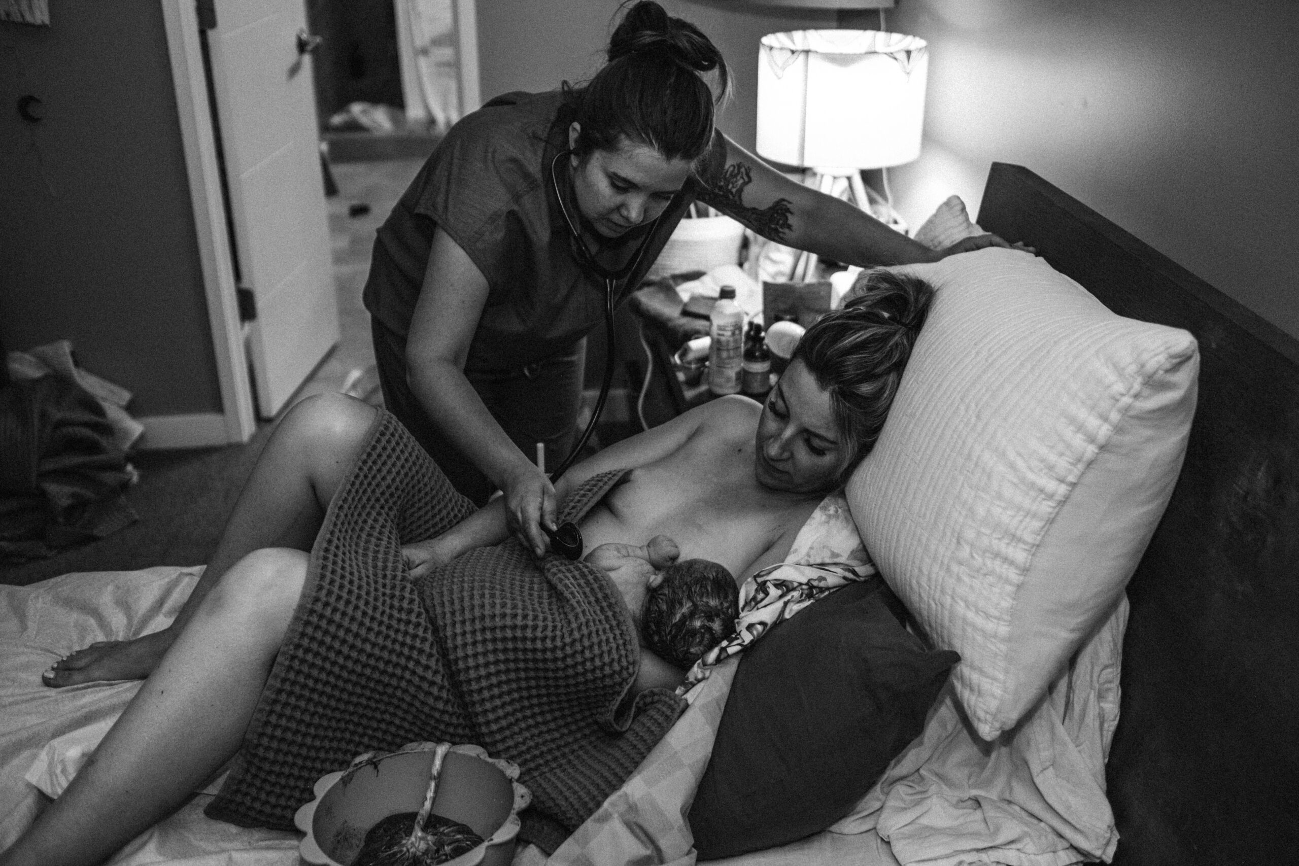 Midwife checking baby boy while he is laying on mom's chest